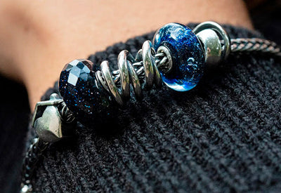 Trollbeads bracelet with the home, siblings, and neverending sliver beads and two blue glass beads on a foxtail bracelet